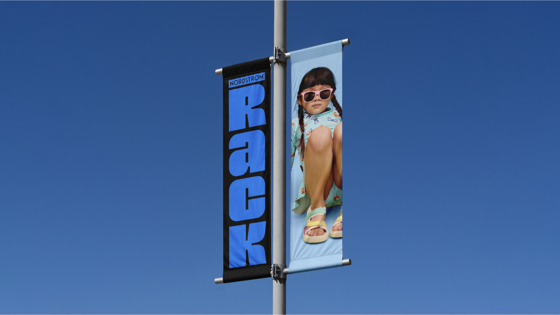 Parking lot banner with vertical Nordstrom Rack logo and fashion photography.